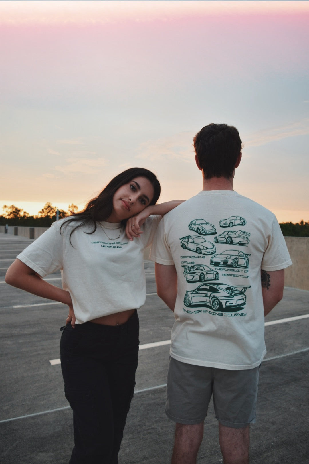 Male and Female Model Wearing White 100% cotton t-shirt featuring green hand-drawn Porsche 911 GT3 RS designs with the text "Destroying Dailys The Pursuit of Perfection A Never Ending Journey," perfect for car enthusiasts.