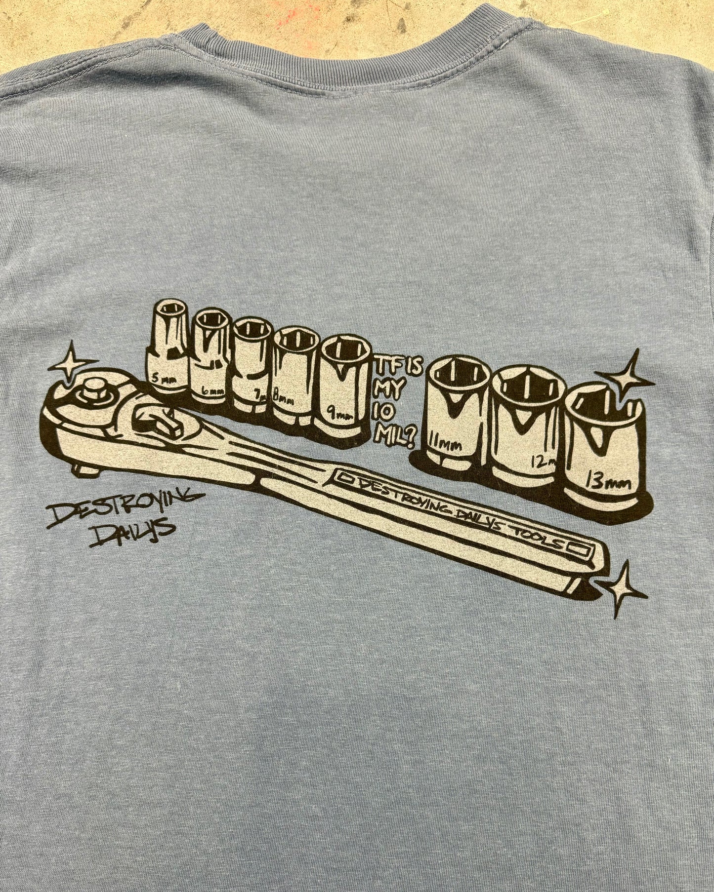 Car mechanic t shirt with a missing 10 Millimeter socket and a socket wrench. T shirt for car guys and car enthusiasts. 100% cotton tee shirt for car guys and car mechanics. Funny Mechanic Shirt with text "TF is my 10 mil?" on the back. Missing 10MM Socket T Shirt for mechanics. Close up back photo