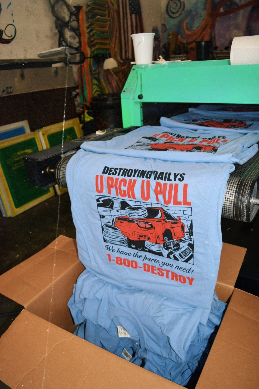 Printing process for light blue 100% cotton t-shirts with a hand-drawn JDM Rx-7 graphic and text "Destroying Dailys U Pick U Pull 1-800-DESTROY," perfect for car enthusiasts.