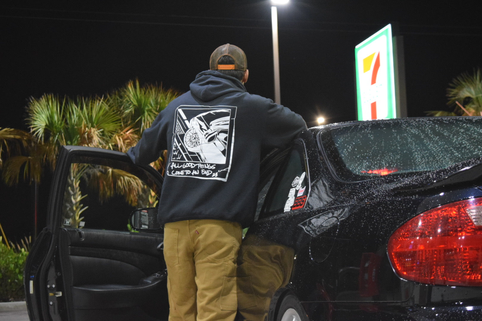 Male Model Car Guy with JDM Car wearing black hoodie made of 50/50 cotton and polyester blend featuring a hand-drawn JDM car with the text "All Good Things Come to an End '23," perfect for car enthusiasts. Jdm hoodie for car guys