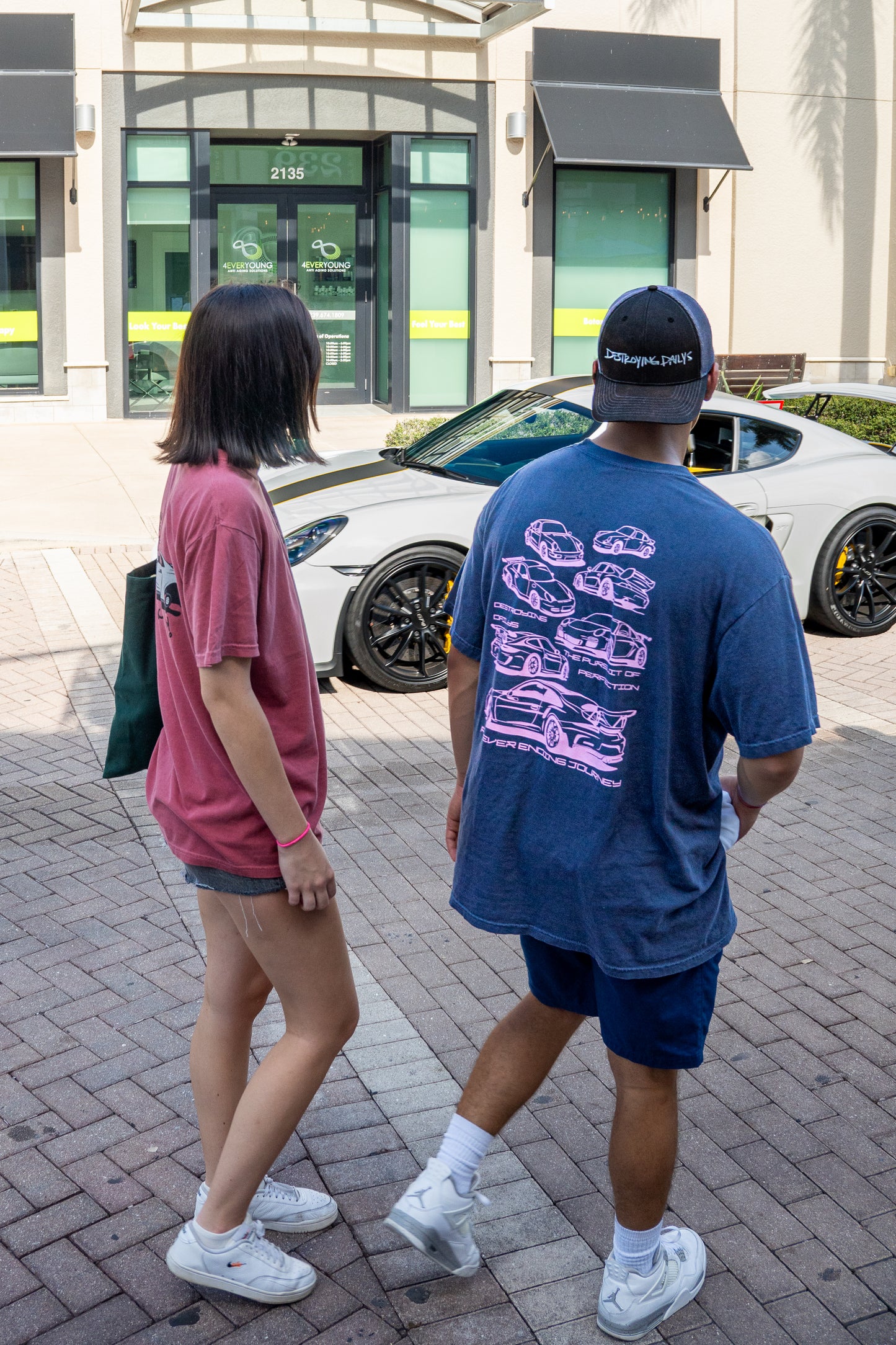 Male Model with Porsche Wearing Navy blue 100% cotton t-shirt featuring hand-drawn Porsche 911 GT3 RS designs with the text "Destroying Dailys The Pursuit of Perfection A Never Ending Journey," perfect for car enthusiasts.