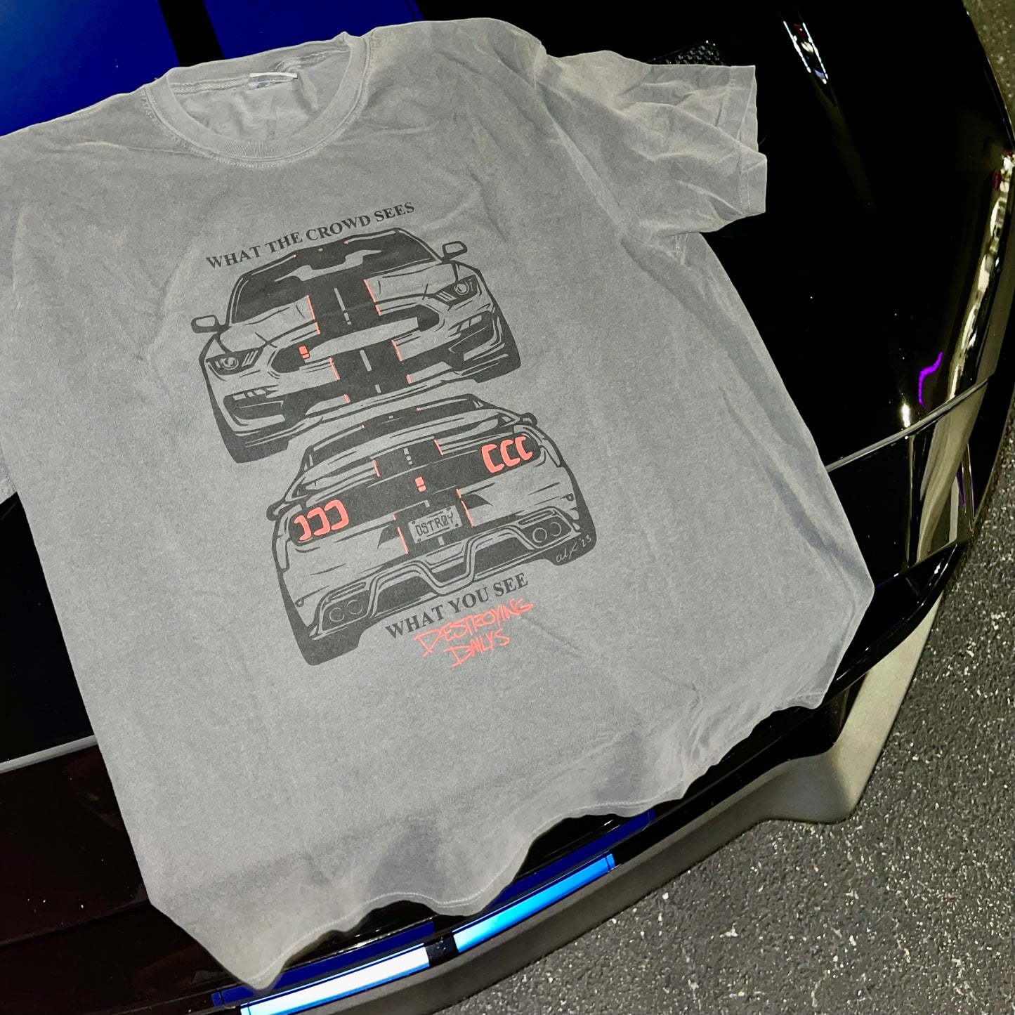 Gray 100% cotton t-shirt featuring a hand-drawn Mustang with the text "What the Crowd Sees / What You See Destroying Dailys," perfect for Mustang enthusiasts. Funny mustang crowd tee for car enthusiasts. Mustang shirt on mustang