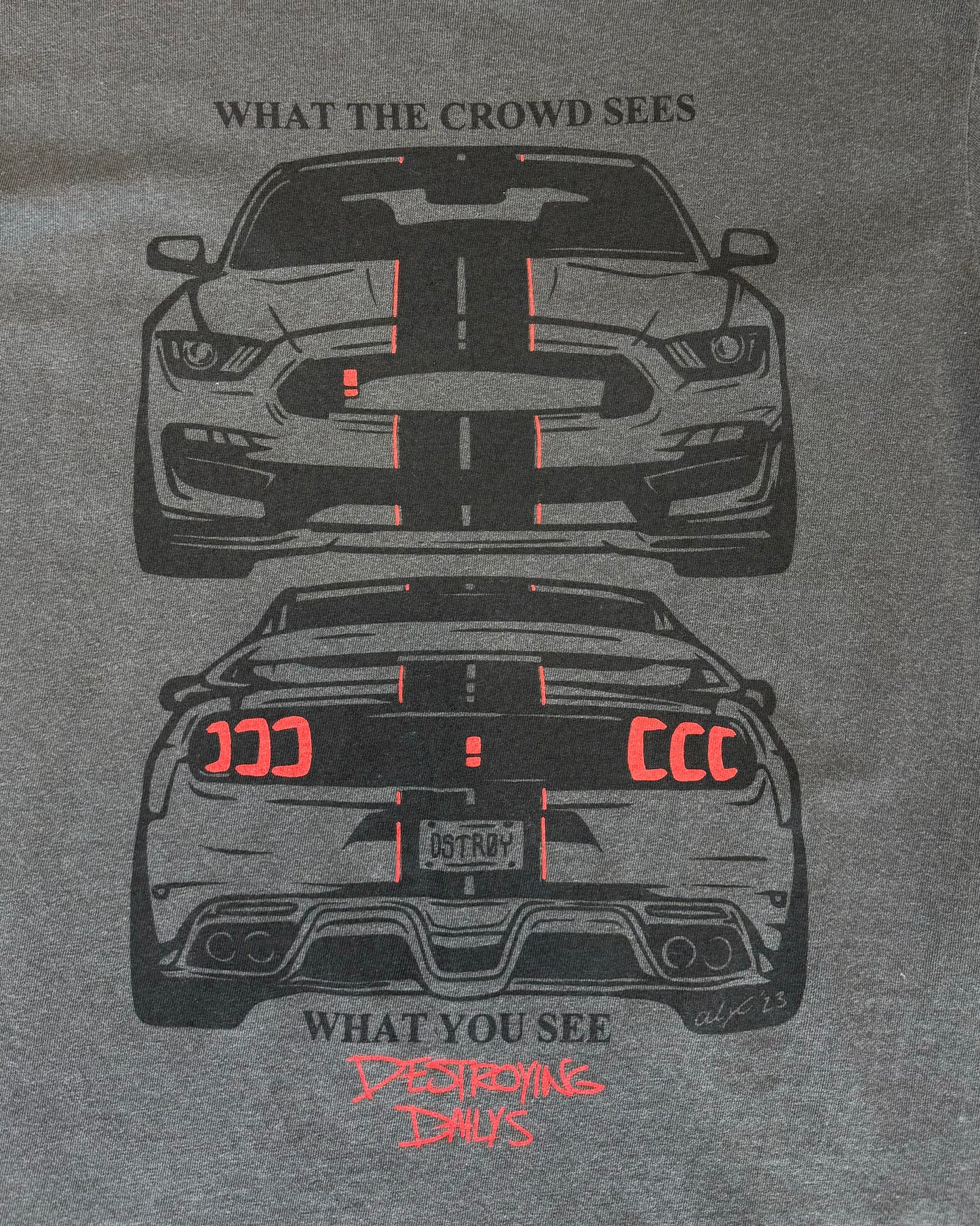 Detailed photo of Gray 100% cotton t-shirt featuring a hand-drawn Mustang with the text "What the Crowd Sees / What You See Destroying Dailys," perfect for Mustang enthusiasts. Funny mustang crowd tee for car enthusiasts