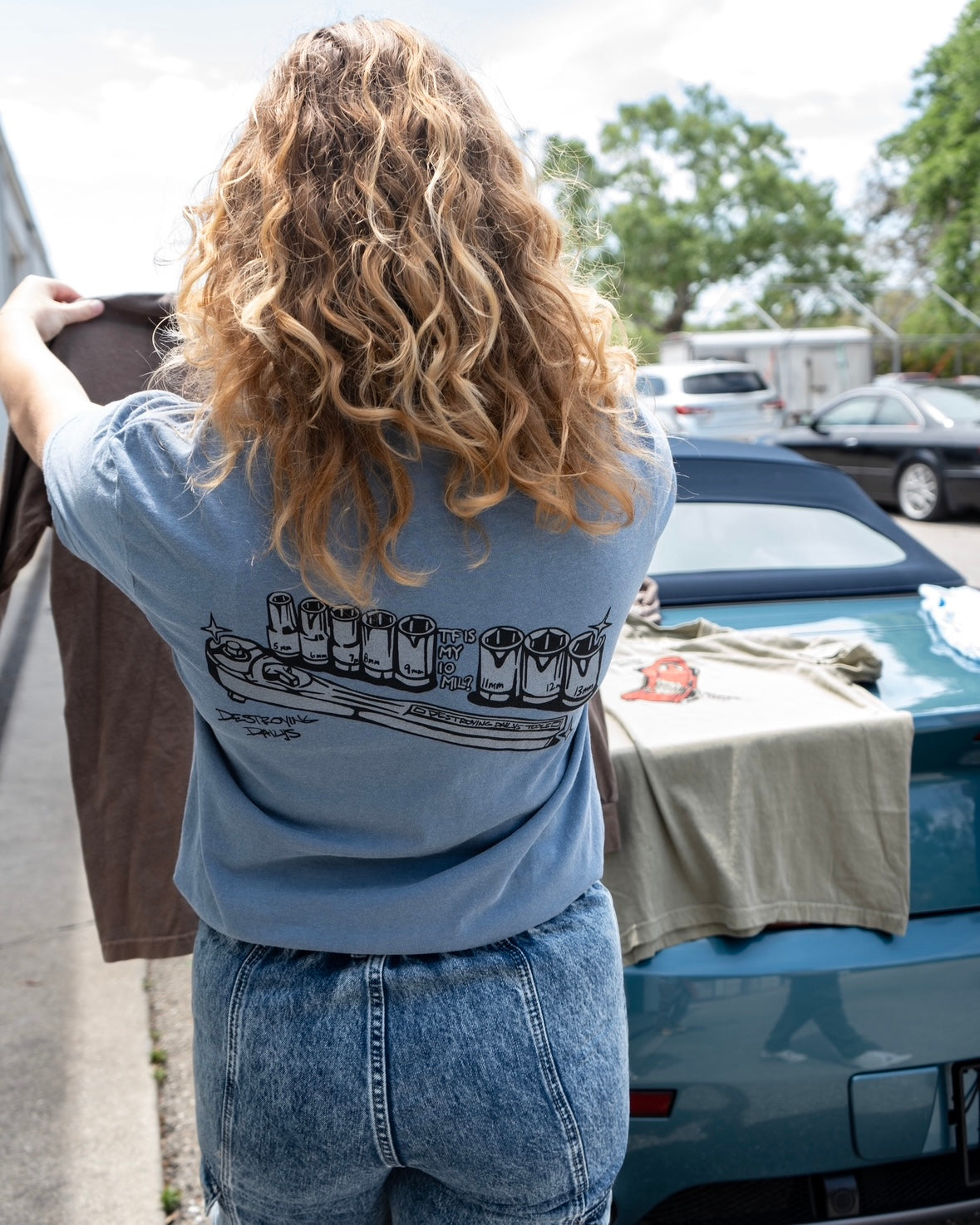 Car mechanic t shirt with a missing 10 Millimeter socket and a socket wrench. T shirt for car guys and car enthusiasts. 100% cotton tee shirt for car guys and car mechanics. Funny Mechanic Shirt with text "TF is my 10 mil?" on the back. Missing 10MM Socket T Shirt for mechanics. Model wearing the T Shirt