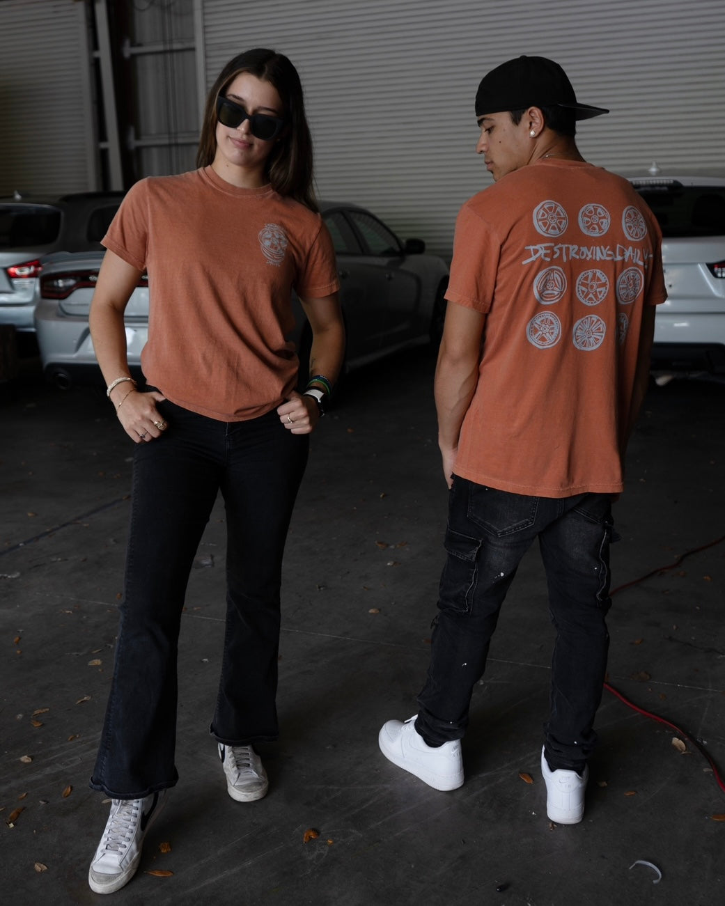 Models Wearing Orange 100% cotton t-shirt featuring a hand-drawn design of JDM wheels with the text "Destroying Dailys," perfect for car enthusiasts.