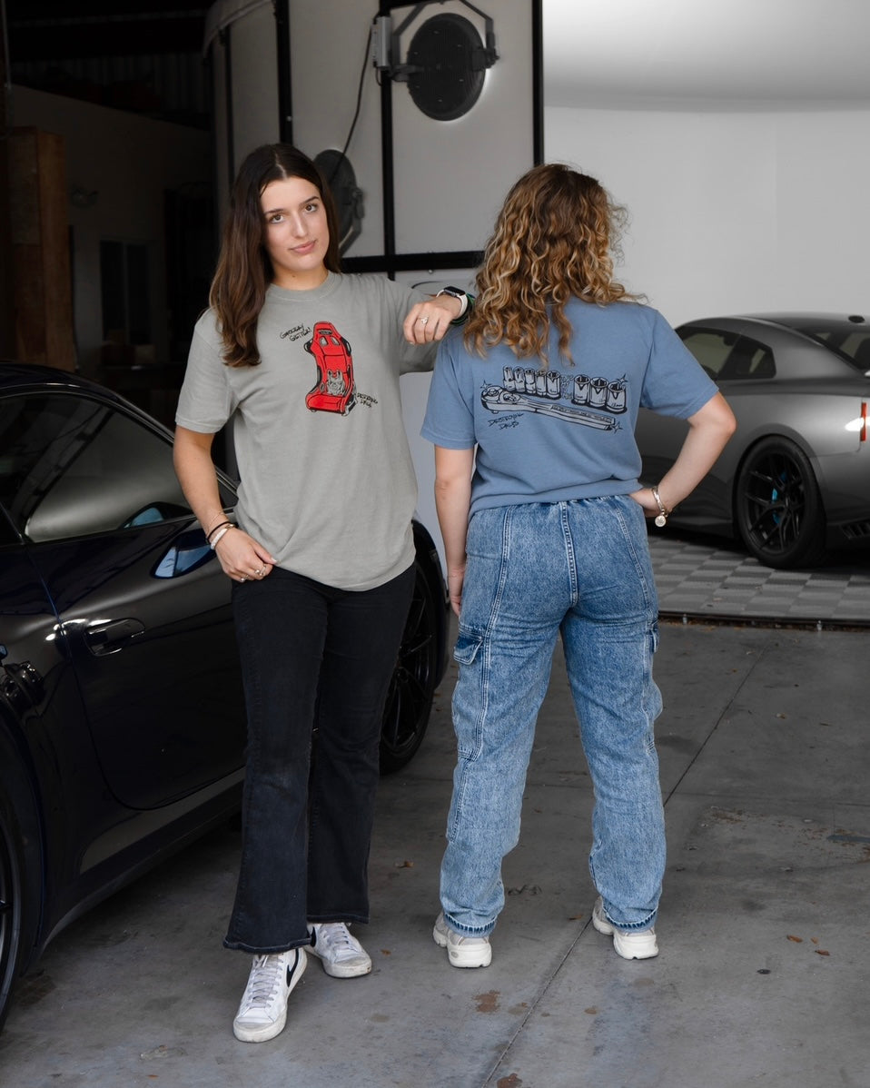 female model wearing tan 100% cotton t-shirt featuring a hand-drawn red racing seat with a grocery bag and the text "Grocery Getter! Destroying Dailys," perfect for car enthusiasts. Funny car shirt for car enthusiasts