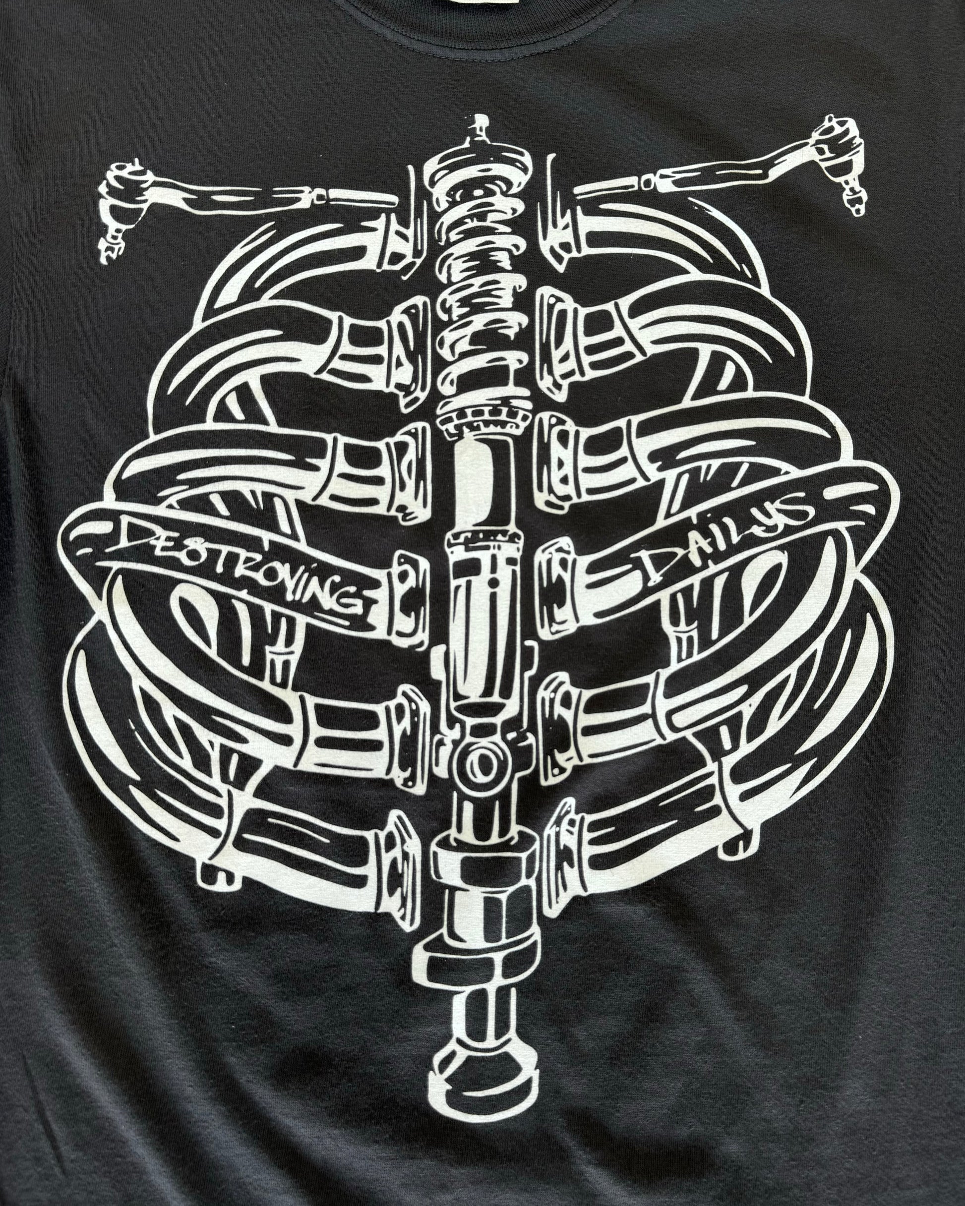 Black T-shirt featuring a hand-drawn design of a human ribcage made from various car parts. The design includes intricate details with text 'Destroying Dailys' incorporated into the ribs, appealing to car enthusiasts. Perfect for car fans, this T-shirt is made from soft 100% cotton, pre-shrunk, and garment dyed for a comfortable fit. Ideal for showcasing your passion for cars with a unique, artistic twist. detailed front close up shop