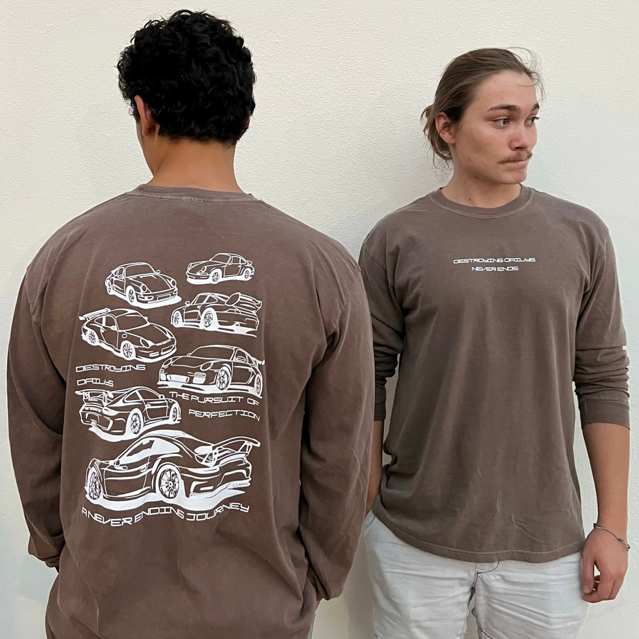 Male Models wearing Brown long-sleeve 100% cotton t-shirt featuring white hand-drawn Porsche 911 GT3 RS designs with the text "Destroying Dailys The Pursuit of Perfection A Never Ending Journey," perfect for car enthusiasts.